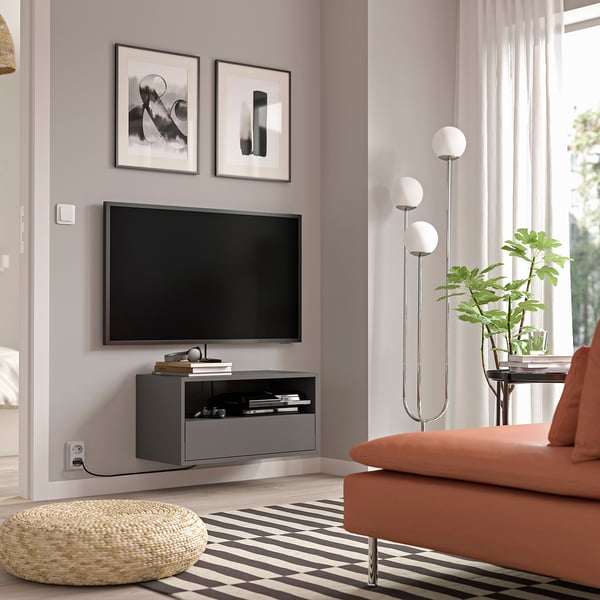 Modern living room with grey EKET wall-mounted tv unit, flat screen, and orange sofa.