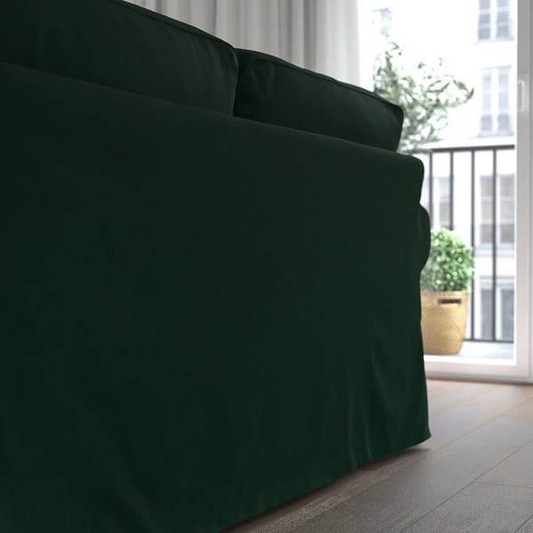 Dark green EKTORP sofa near window, with lush plants outside.