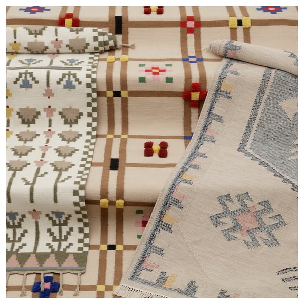 Handwoven wool rug, white with colourful flowers, braided edges.