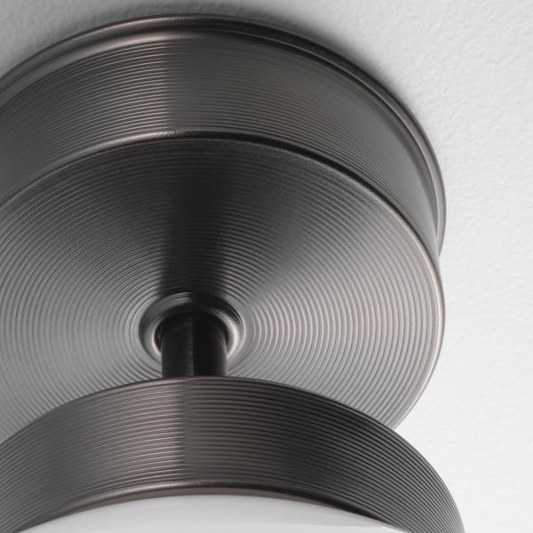 Modern ceiling light with sleek metal design. Circular glass shade emits even lighting, mounted securely on a polished rod.