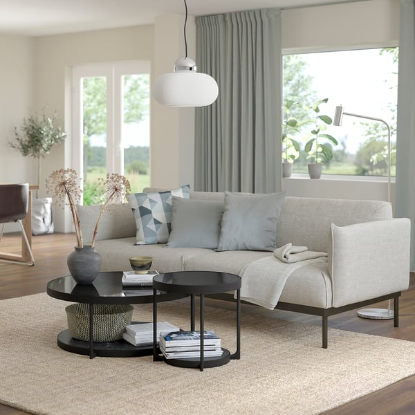 Bright living room with large windows, a beige FRÖTORP sofa, black coffee table, white pendant light, grey curtains, and plants.