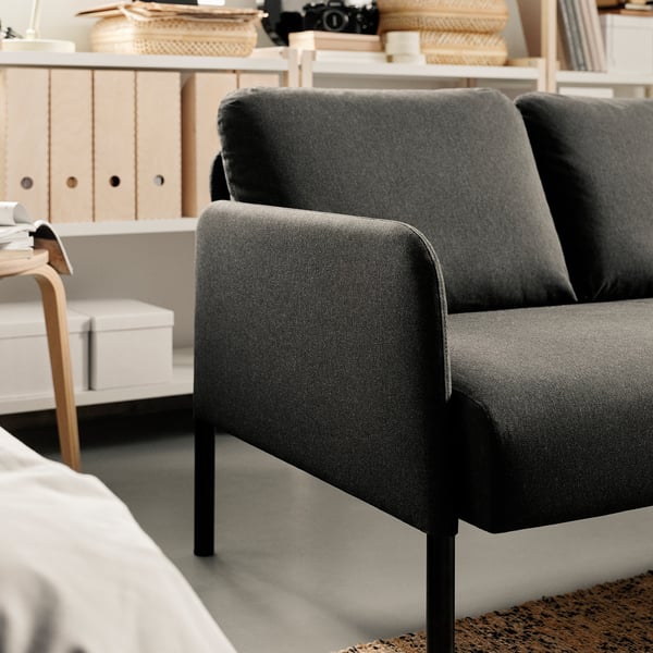 A modern grey sofa, GLOSTAD, with sleek metal legs, providing comfortable seating. The sofa a minimalist design, suitable for small spaces.