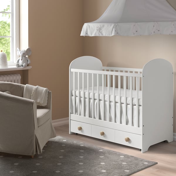 Cosy nursery with GONATT crib, armchair, rug, soft lighting.