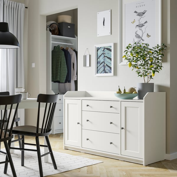 Modern, white HAUGA sideboard drawers and cabinets, showcasing a sleek design with decorative items and greenery on top.