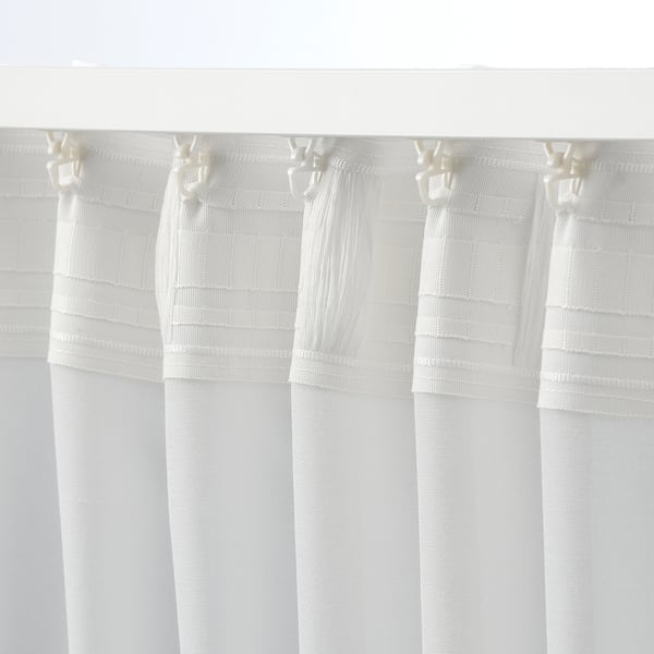 White curtains with intricate header design hang elegantly, showcasing their multi-way hanging option and fine woven texture.