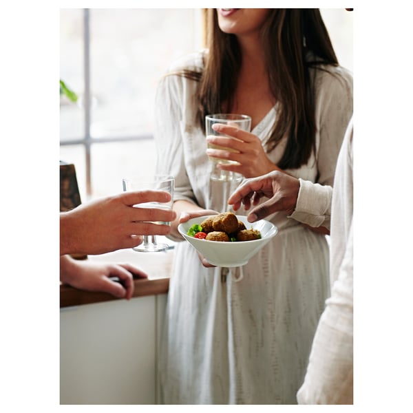 Two people enjoy IKEA 365+ white bowls with food and drinks near a window.