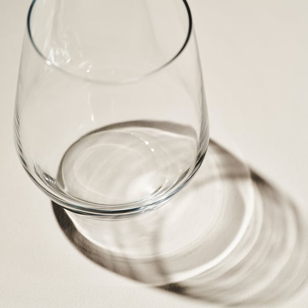 Clear wine glass with wide bowl on reflective surface. Dishwasher-safe and durable, showcasing clarity and aroma.
