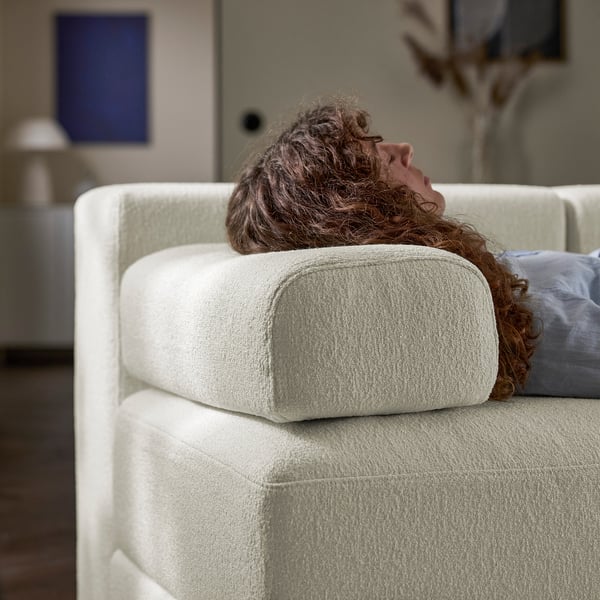 Person resting head on large, white cushioned sofa. The sofa deep seats, supportive comfort, and soft headrest pillows.