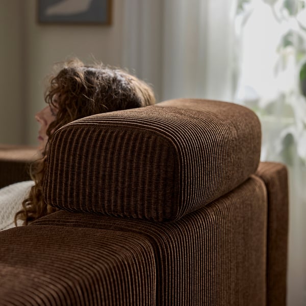 Person resting on JÄTTEBO sofa with headrest cushion.