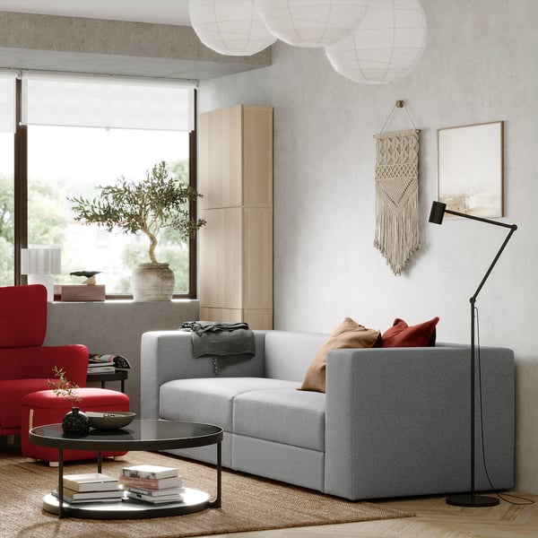 Modern living room with JÄTTEBO grey sofa, red chair, wooden cabinet, and large window.