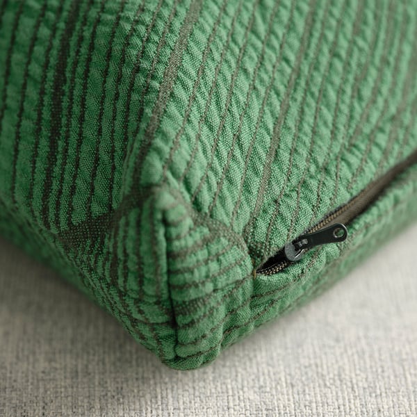 Close-up of green JÄTTEGRAN cushion cover, showcasing its textured, nature-inspired pattern and durable zip.