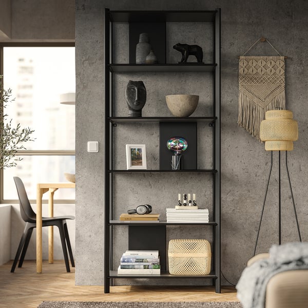 Modern living room with JÄTTESTA black bookshelf showcasing vases, bowls, and decor. Bamboo shelves, metal legs, stylish design.