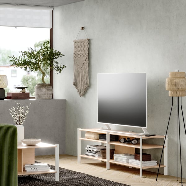Modern living room with JÄTTESTA white tv stand, bamboo shelves, sleek design, flat screen tv, green chair, indoor plant, woven rug.