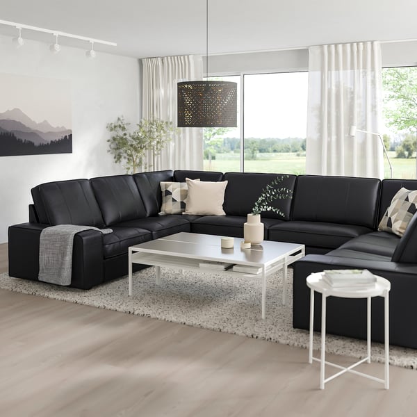 Modern living room with large black l-shaped KIVIK sofa, white coffee table, and large window, offering a cosy and stylish space.