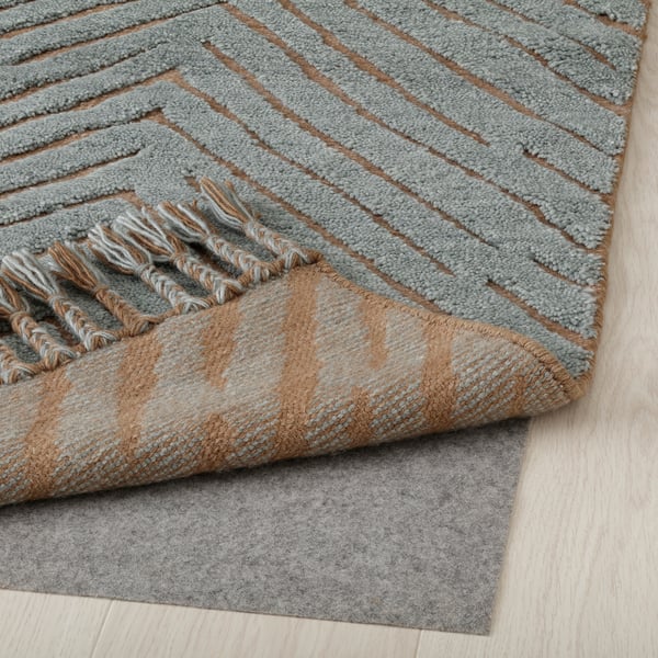 Striped wool rug with fringes and non-slip mat underneath, demonstrating rugs safety feature.