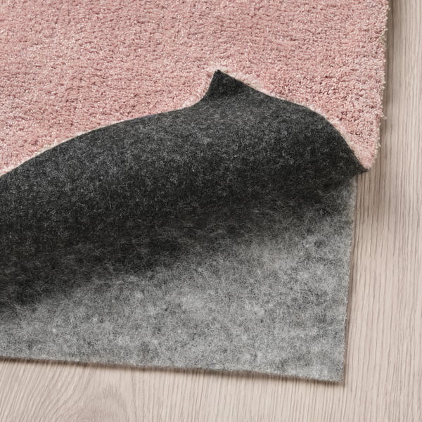 Rug with grey felt underlay on wooden floor.