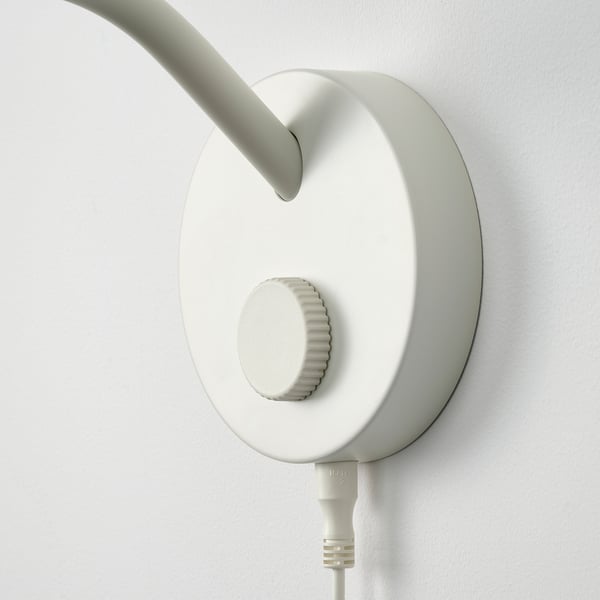 A minimalist white wall-mounted lamp with adjustable arm and a round shade.