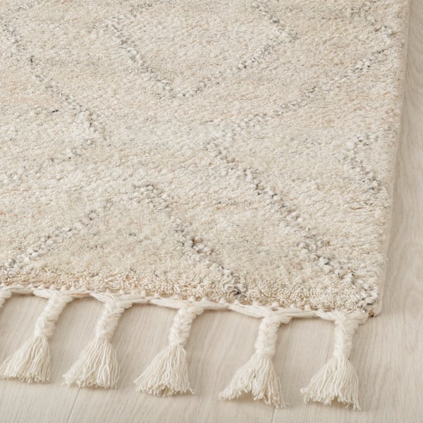 Handcrafted rug featuring soft, high pile wool with braided fringe, exuding quality and comfort.