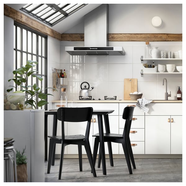 Modern kitchen with black & white decor, black dining set, stainless appliances, wooden accents.