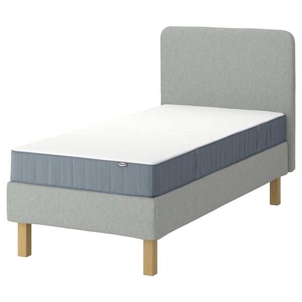 IKEA lyngor bed in light grey with blue mattress, featuring a soft headboard and wooden legs.
