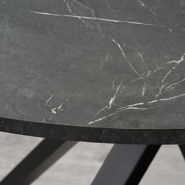 Black circular tabletop with white veining on a sturdy, dark metal frame.