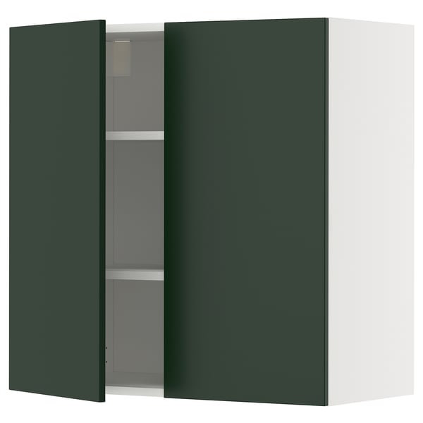A green kitchen cabinet with one door open, revealing adjustable shelves inside.