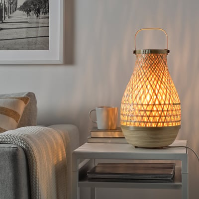 MISTERHULT lamp on side table, surrounded by books and a mug.