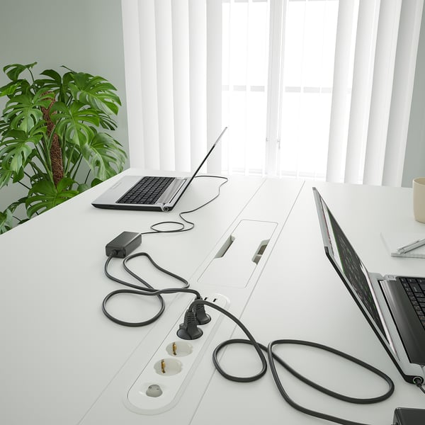 Minimalist office desk with built-in power outlets and cables. Ideal for meetings, includes footrest for comfort.