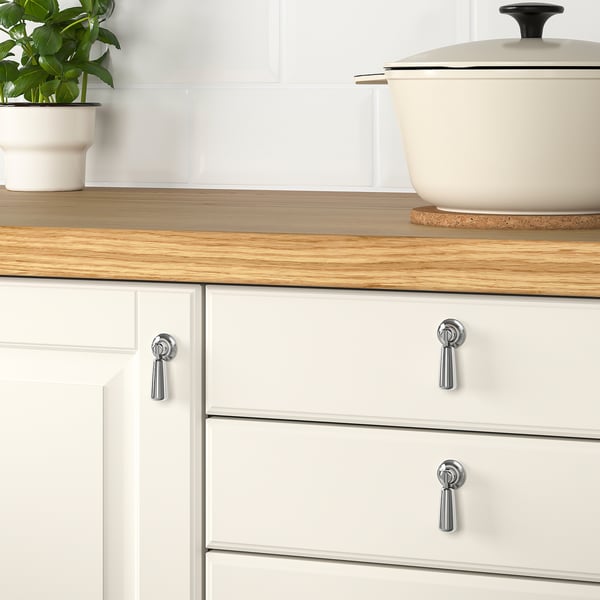 Wooden counter, white cabinets, plant on trivet.