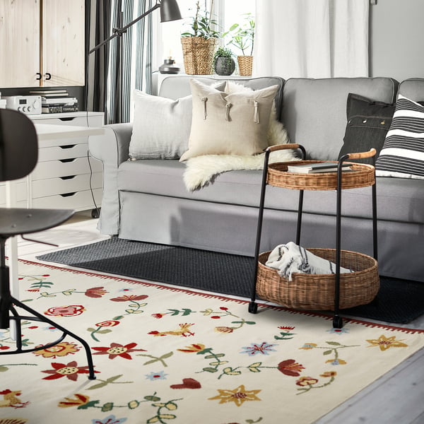Cosy living room with grey sofa, colourful floral rug, and wicker side table.