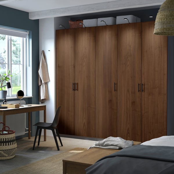 Minimalist bedroom with large walnut PAX wardrobes, desk, and window.
