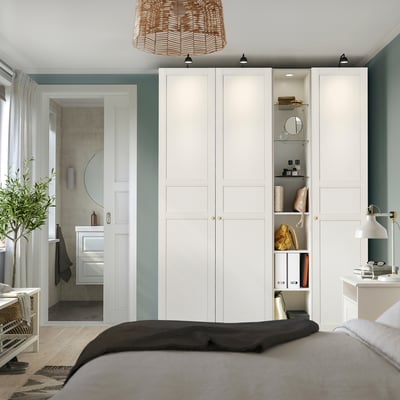 Bedroom with large white PAX wardrobe, multiple shelves, and minimalist design against teal wall.