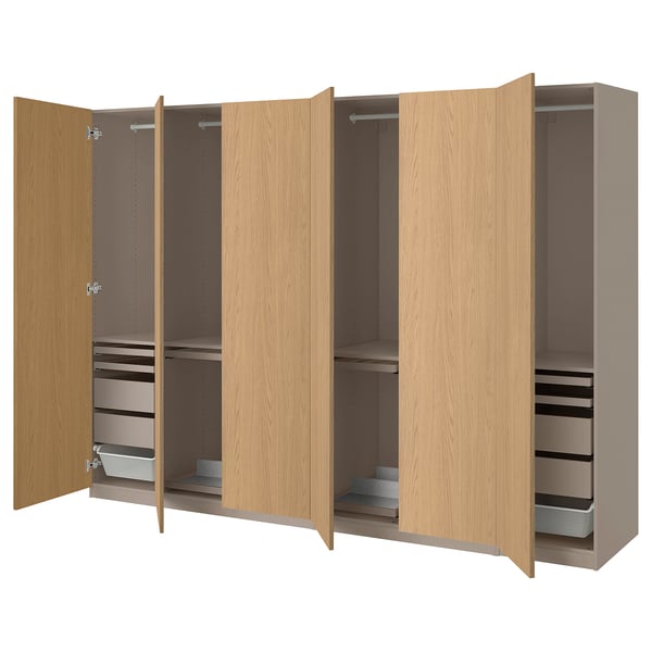Wooden PAX wardrobe, light brown, modular design with open doors revealing adjustable shelves, drawers, and hanging space.