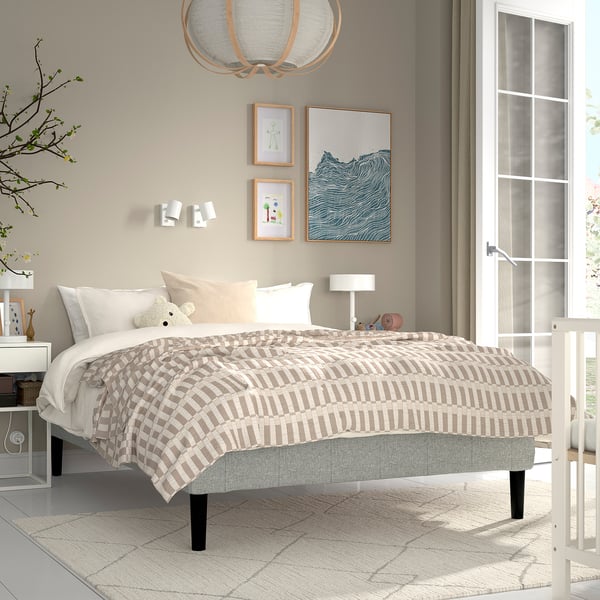 Neutral bedroom with RENFJÄLLET bed, chequered blanket, teddy bear, artwork, bedside table.