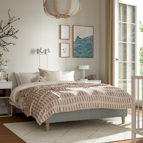 Modern bedroom with beige & white decor. RENFJÄLLET bed, plaid bedspread, two nightstands with lamps, gold light fixture, large window.