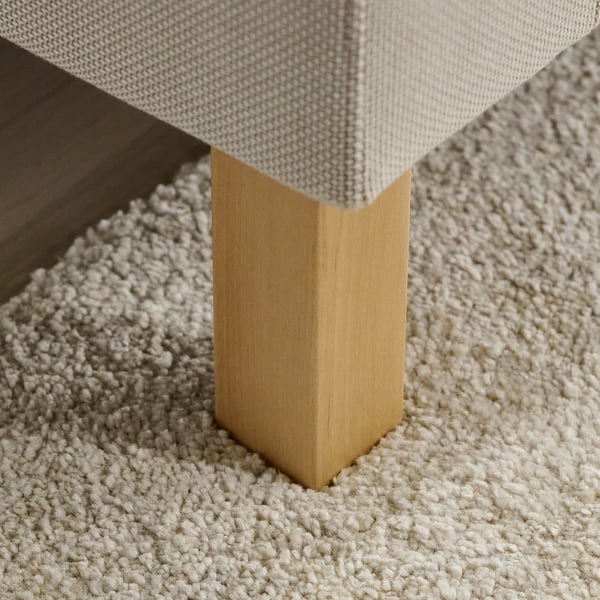 A sofa leg seen at an angle, showcasing its sturdy build and golden finish, resting on a textured off-white carpet.