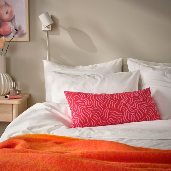 Vibrant red SANDMOTT cushion on bed, rectangular, patterned, white background.
