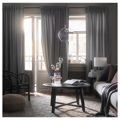 Modern living room with grey SANDSVINGEL curtains, black furniture, and a central coffee table, illuminated by natural light.