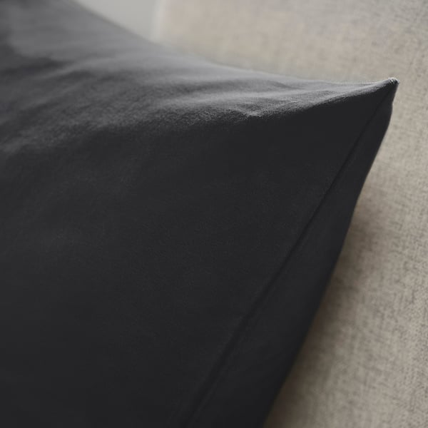 Dark cushion cover made of soft, textured cotton velvet. Close-up shows smooth, even stitching and rich fabric quality.