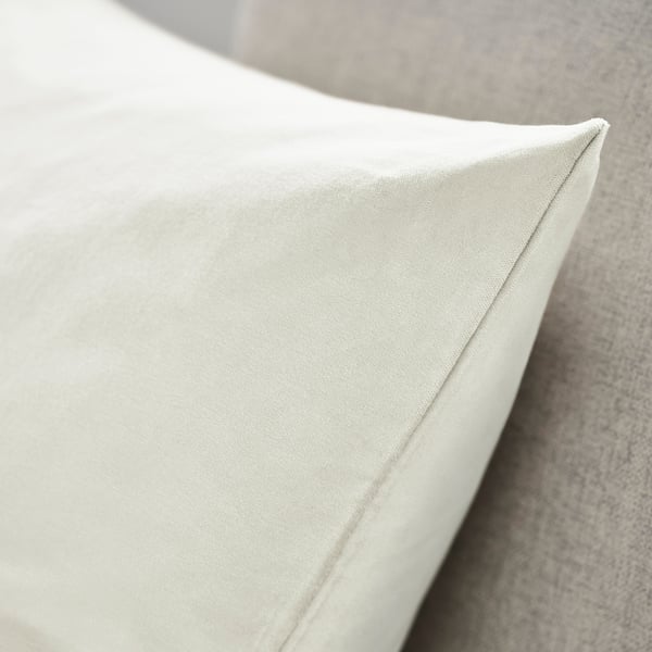 Close-up of plush, velvety cushion cover on a sofa. Smooth texture and neatly finished edges visible.