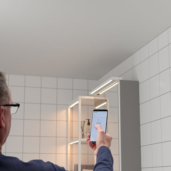 Person using smartphone in bathroom with led lights.