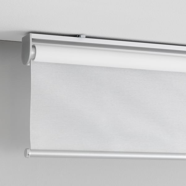 Cordless white roller blind with slow-up feature, mounted on wall.