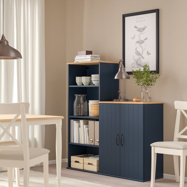 Navy SKRUVBY sideboard, open shelves, lamp, books, between chairs.