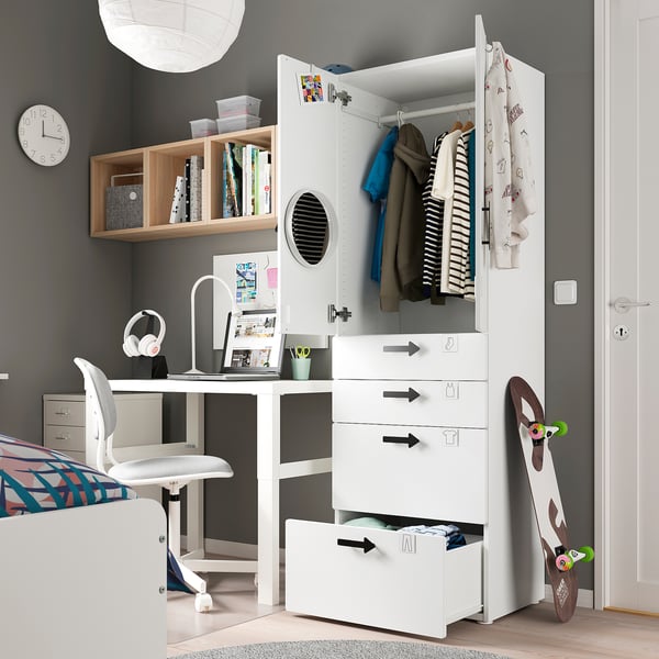 Modern teen bedroom with white SMÅSTAD wardrobe and desk, grey walls, colourful decor, and skateboard.