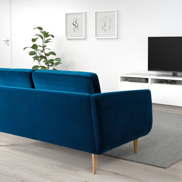Modern living room with teal sofa, tv stand, plant, & abstract art.