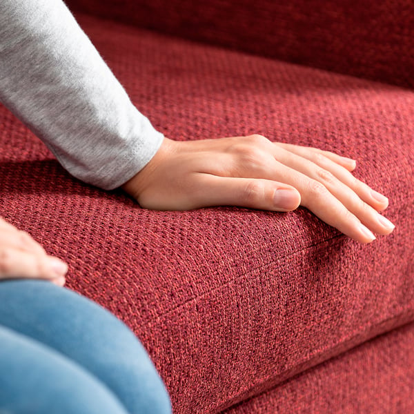 Person placing hand on sofa, feeling soft, high-quality fabric.