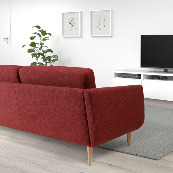 Modern living room with red sofa, tv, plant.