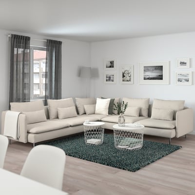 Modern living room with large beige SÖDERHAMN sectional sofa, dark curtains, and wooden floor. Decorated with framed photos and a plant.