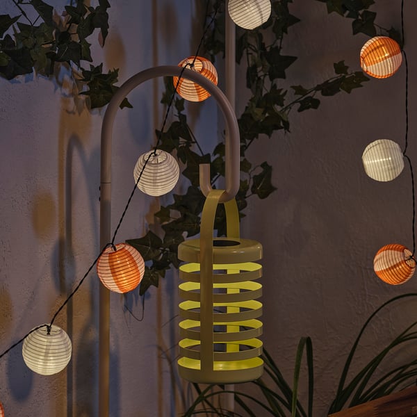 A decorative SOLVINDEN outdoor light with multiple lanterns, powered by solar energy, shedding warm light at night.