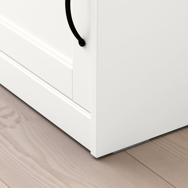 White cabinet with black handle on light wood floor. Clean, modern design visible.